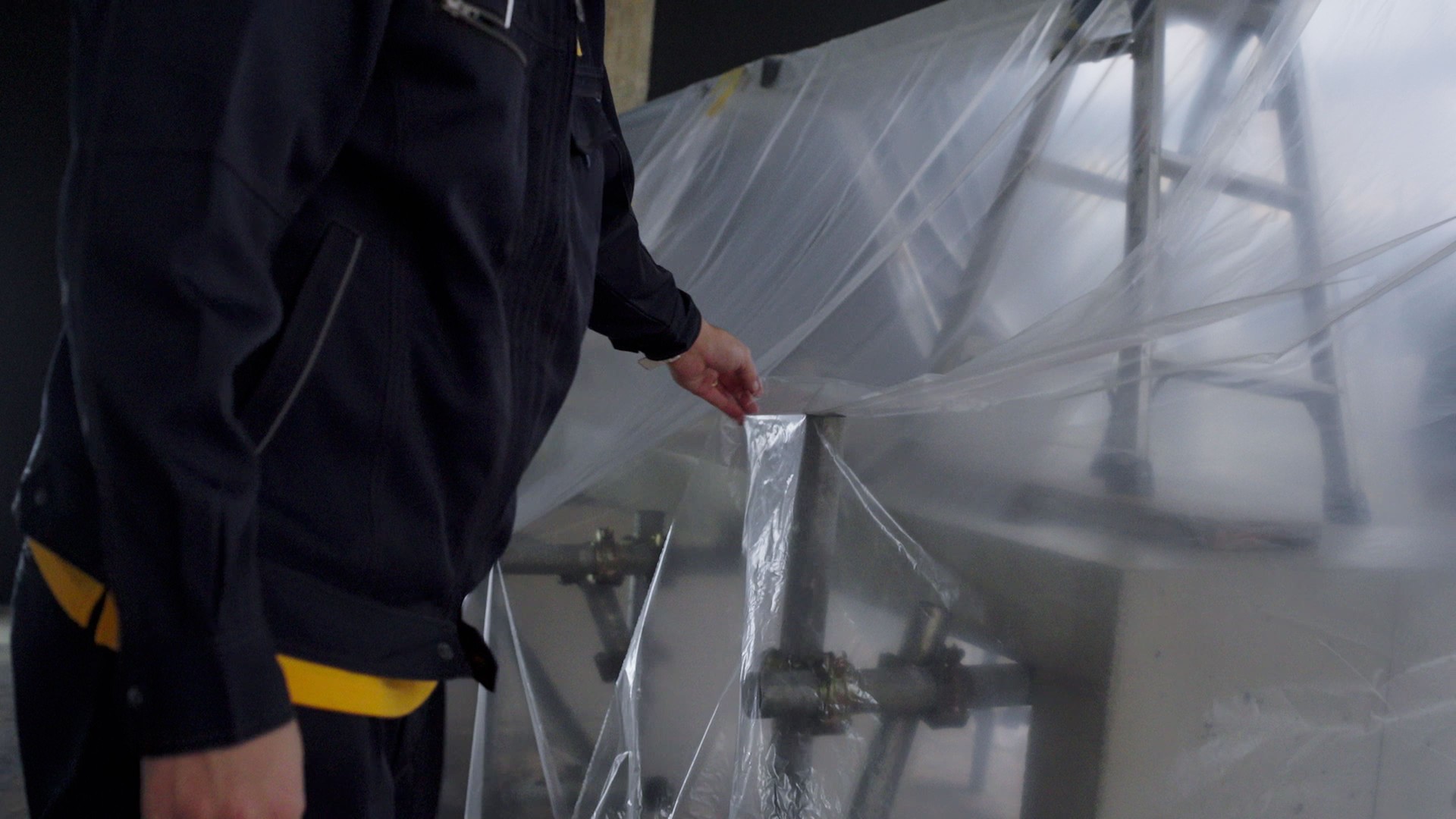 Japanese men cover the scaffold with vinyl.